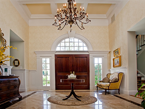 photo of grand foyer with custom stained doors, designer wallcoverings and painted woodwork and ceiliing