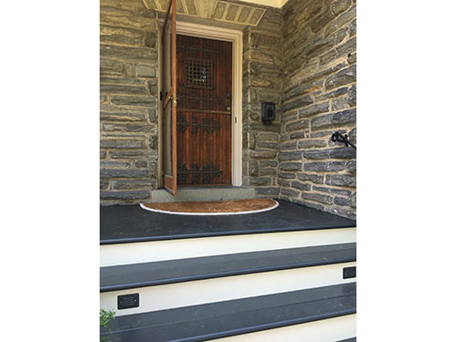 photo of front portico with custom stained door , stone walls and victorian blue deck and cream risers