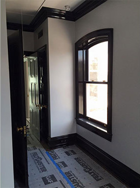photo of hallway with white walls, window, wood work and door on right and door on left finished in high gloss black.
