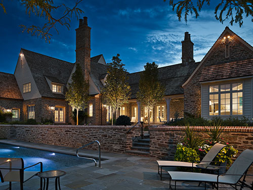 photo of exterior of house with pool at twilight