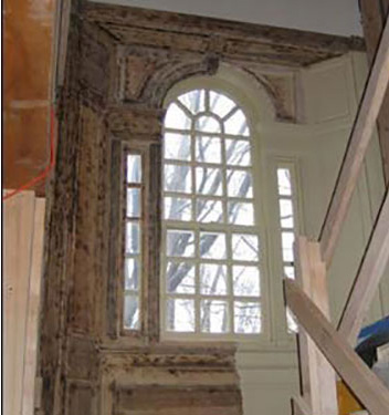 photo of ornate multi-paned arched window interior half way in process of lead paint removal