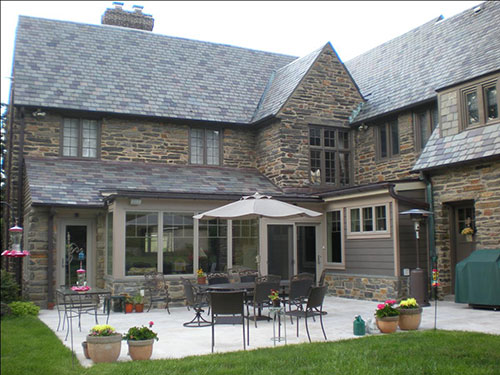 photo of rear of stone home with patio and furniture