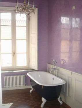 photo of bathroom with claw foot tub painted dark blue, white wainscotting, lavender venetian plaster walls