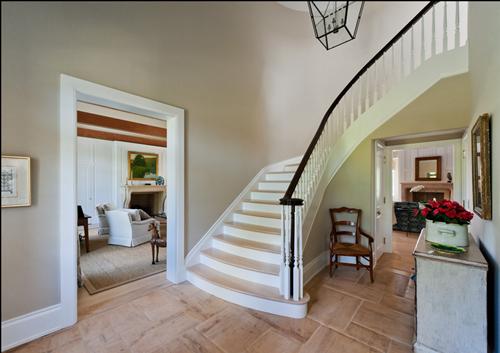 photo of foyer with curved staircase, wall papered walls, dark walnut finish on hand rail